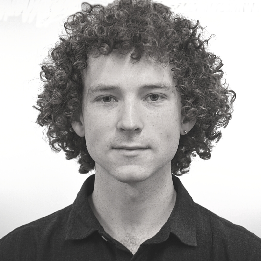 A young man with curly hair wearing a dark shirt.