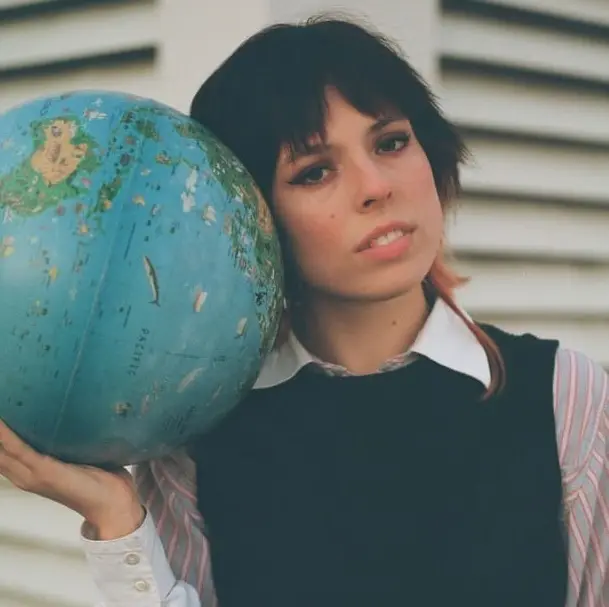 A woman holding a globe near her shoulder.