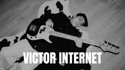 Black and white photo of a man with a bass guitar and a shadows behind him.